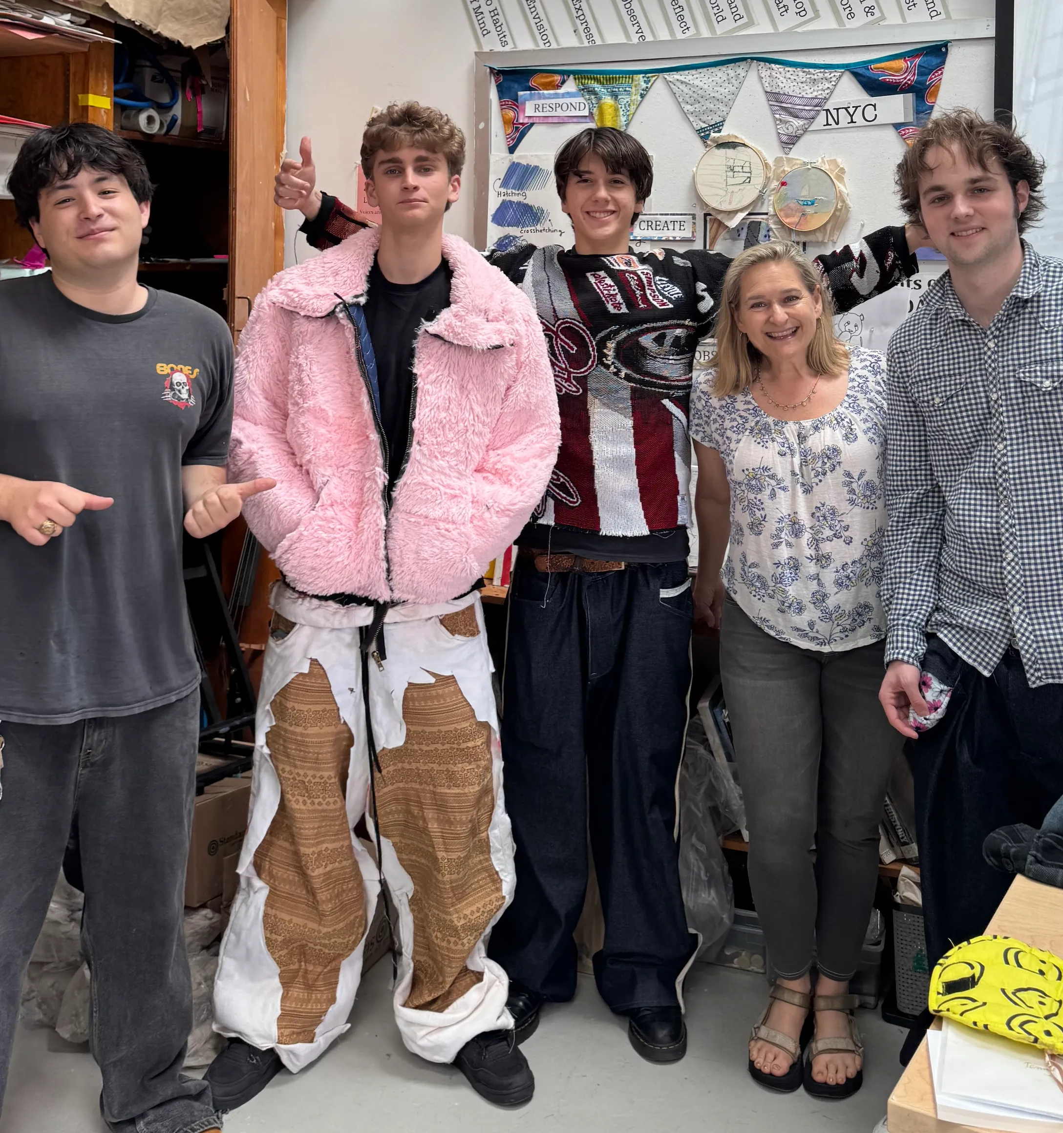 Dr. Nell Daniel stands with four students wearing handmade patchwork jackets and trousers in a studio.