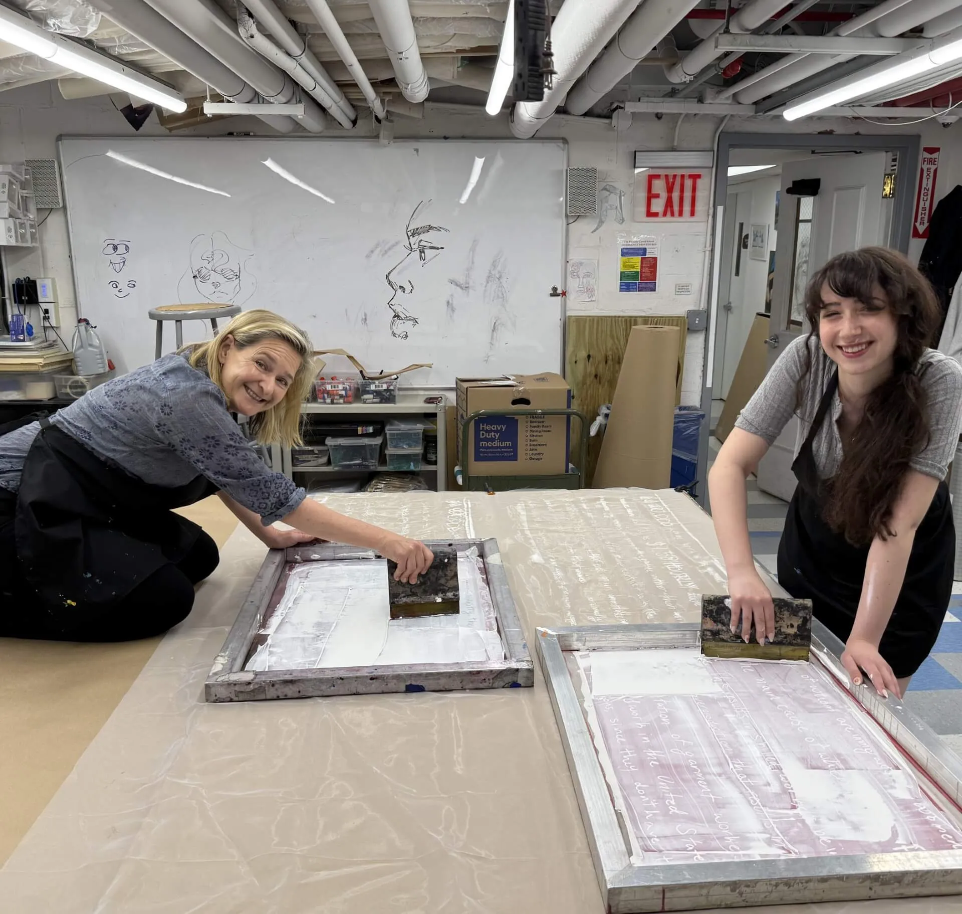 Dr. Nell Daniel and a student pull squeegees across screen-printing frames in a print studio.