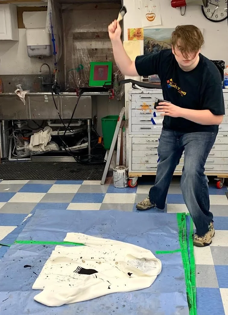 Art student experimenting with paint techniques in a studio setting, demonstrating creative process and exploration—key elements evaluated in college art portfolios.